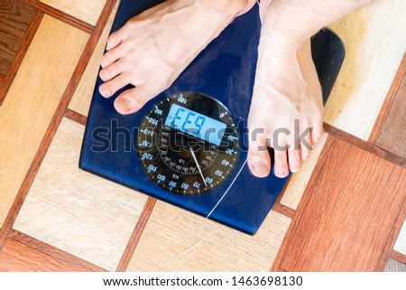 person's bare feet standing on the digital weghs scale, diet concept