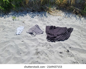 A person's clothes left on the sand at a beach.