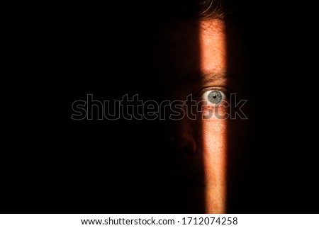 A person's face that has only partially been lit up due to looking through a crack in a doorway. The male witness could have seen many things in the other room
