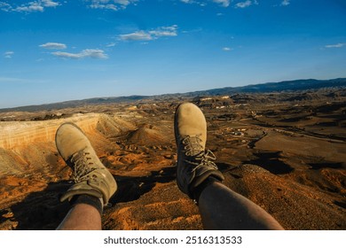 A person's feet dangle from a paraglider or hang glider with a beautiful landscape in the background. - Powered by Shutterstock