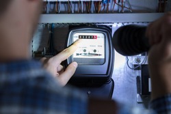 Person's Finger Pointing To Electric Meter Reading Using Flash Light
