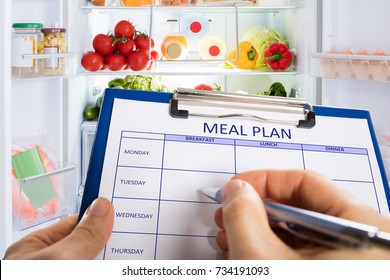 Person's Hand Filling Meal Plan Form On Clipboard
