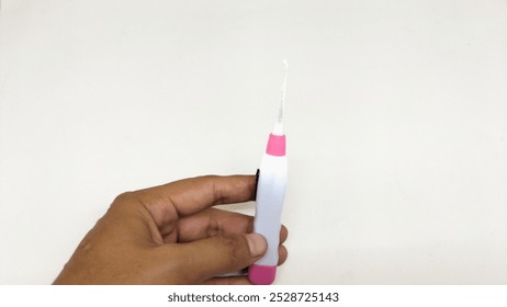 a person's hand is holding a pink and white Ear Cleaner that has an LED light isolated on a white background - Powered by Shutterstock