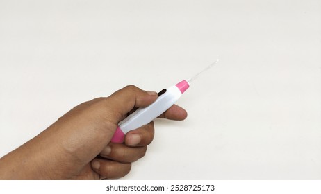 a person's hand is holding a pink and white Ear Cleaner that has an LED light isolated on a white background - Powered by Shutterstock