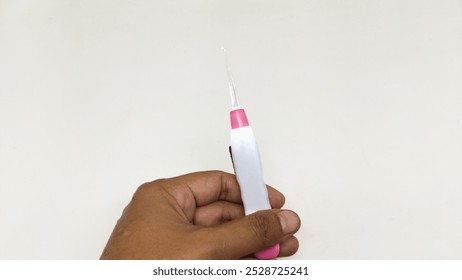 a person's hand is holding a pink and white Ear Cleaner that has an LED light isolated on a white background - Powered by Shutterstock