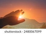 Persons hand in nature reaching out to touch the warm sun light. Spiritual, light, healing energy concept	