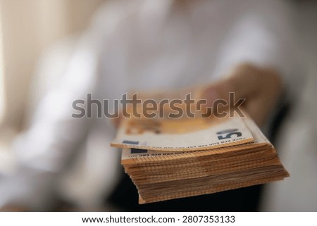 Person's hand offering a substantial stack of fifty euro banknotes, symbolizing financial exchange, payment, wealth, banking, lending, and economic growth in a business context