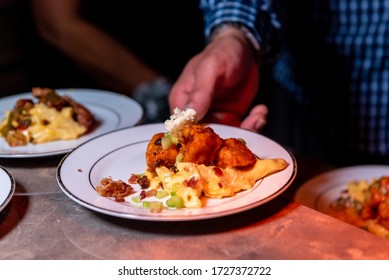 A Person's Hand Putting Plates Of Delicious Food On A Table