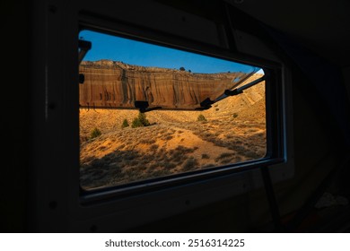 A person's hand reaches out from the window of a camper van, the desert is visible. - Powered by Shutterstock