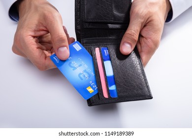 A Person's Hand Removing Credit Card From Wallet On White Background