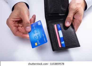 A Person's Hand Removing Credit Card From Wallet On White Background