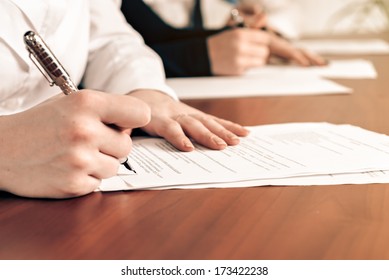 Person's Hand Signing An Important Document