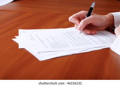 person's hand signing an important document
