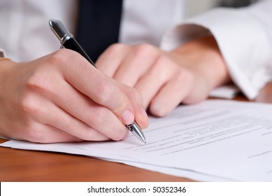 Person's Hand Signing An Important Document