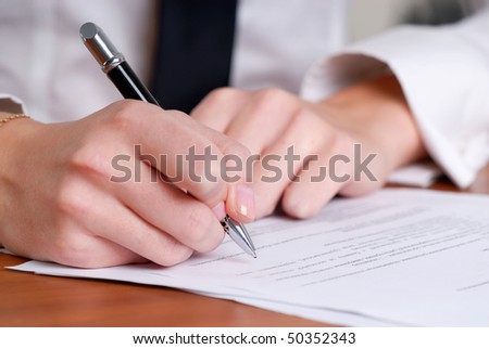 person's hand signing an important document