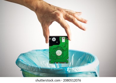 Person's hand throws a computer hard disk into the trash bin. Loss of information, obsolescence of computer technology, concept