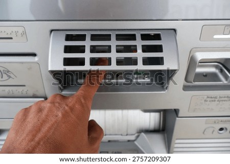 ​A person's hand typing a PIN code on an ATM machine keypad at a bank to authorize a secure financial transaction and access banking services safely.
