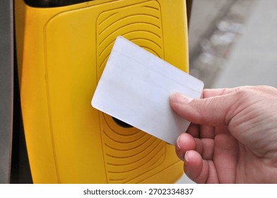 A person's hand validating a card in a validation machine; the card is blank, without any inscriptions, and an illustration is to be added
