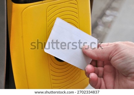 A person's hand validating a card in a validation machine; the card is blank, without any inscriptions, and an illustration is to be added