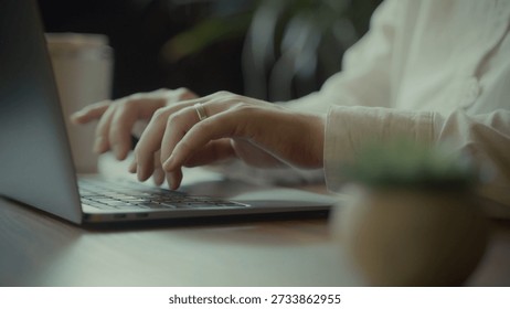 A person's hands actively engaged in typing on a modern laptop, with a subtle focus on a ring worn on their finger, suggesting personal touch or commitment
