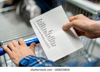 Person's Hands Holding A Shopping List Paper Sheet And Check Buying Products In Grocery Store