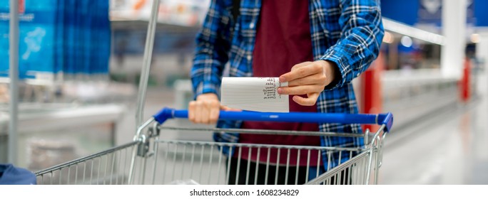 Person's Hands Holding A Shopping List Paper Sheet And Check Buying Products In Grocery Store