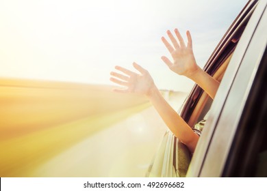 Person's hands out of the car window driving down a country road