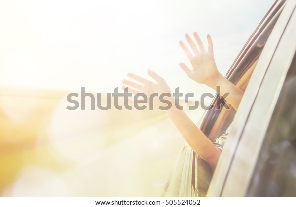 Person\'s hands out of the car window driving down a\
country road