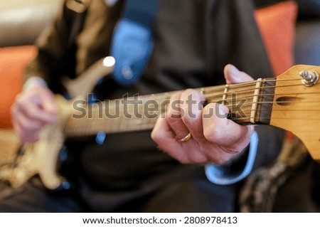 Person's hands playing chords on an electric guitar, creating music
