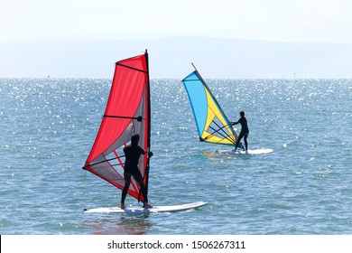 persons learning to windsurf off the island Alameda in the San Francisco Bay. Windsurfing a surface water sport that combines elements of surfing and sailing.