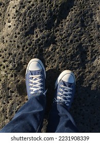 Person's point of view looking down on their shoes while standing on a rock