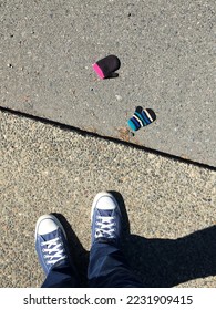 Person's point of view looking down at two lost gloves on a sidewalk