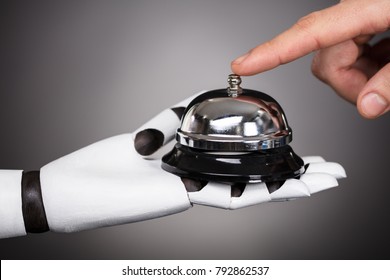 Person's Ringing Service Bell Hold By Robot On Grey Background