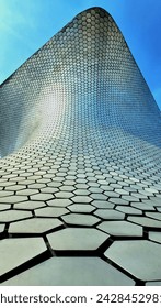 perspective angle view of the Soumaya museum where you can see hexagons forming a pattern under a blue and sunny sky