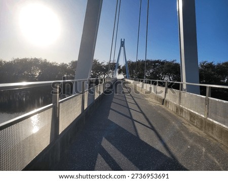 A perspective captured while walking across a bridge overlooking a calm river below. The leading lines of the bridge guide the eye toward the horizon, while the gentle flow of water and surrounding scenery create a sense of movement and depth. This viewpoint conveys journey, transition, and connection between places, making it ideal for themes of travel, exploration, infrastructure, and scenic landscapes.