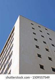 perspective corner view of an old white 1960s concrete office block against a blue sky