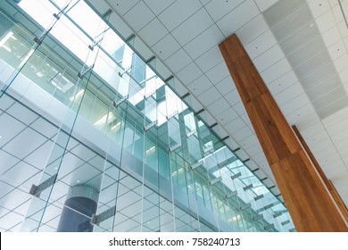 Perspective And Directly Below Hospital Or Office Lobby Background Interior View Toward Reception Hall, Modern Hall Space With White Ceiling Wood Column And Building Glass Wall Window.