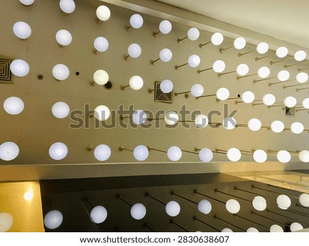 Perspective low angle view of multiple round white globe lights arranged in a grid installation on an indoor ceiling