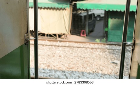 A perspective from an open train door looking out at tracks and market stalls.