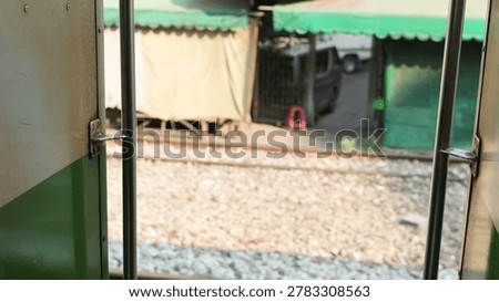 A perspective from an open train door looking out at tracks and market stalls.