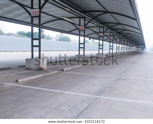 perspective of\
outdoor empty parking lot with steel tube structure and metal sheet\
roof, number sign of lot\
each