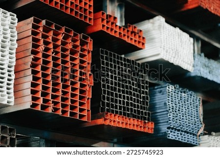 A perspective shot of a massive pile of square steel tubes in a hardware store. The metal profiles display a rugged texture suitable for industrial design themes. This photo captures the essence of the construction industry, emphasizing the stockpile of raw materials ready for fabrication and welding projects.