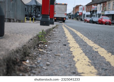 Perspective shot of road surface with pavement, double yellow lines and cars parked in the distance