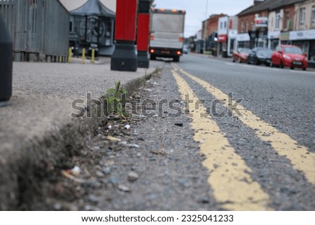 Perspective shot of road surface with pavement, double yellow lines and cars parked in the distance