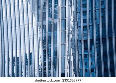Perspective and underside angle view to textured background of contemporary glass facade of achitecture building skyscrapers with light reflect of sky and cloud. (Detail curve shape of glass mullion)