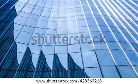 Perspective and underside angle view to textured background of contemporary glass facade of achitecture building skyscrapers with light reflect of sky and cloud. (Detail curve shape of glass mullion)