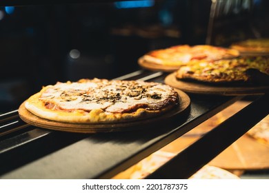 perspective view closeup of different kinds of pizza on wooden plates on the shelves of street food shop window - Powered by Shutterstock