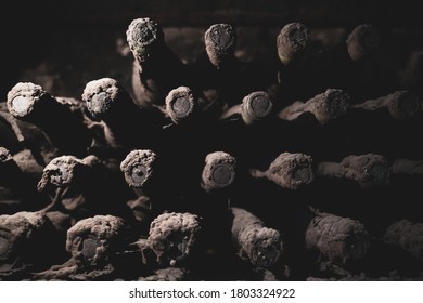 perspective view closeup of stacked aged wine bottles ancient collection covered with soft black mold and spiderweb in vintage wine cellar