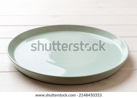 Perspective view of empty blue plate on wooden background. Empty space for your design.