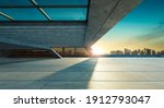 Perspective view of empty concrete floor and modern rooftop building with sunset cityscape scene. Mixed media